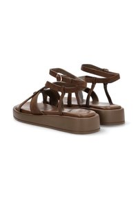 Sandalias de plataforma de ante marrón con diseño de tiras en T, correas de tobillo ajustables y una plantilla lisa y texturada. Suela de goma plana.
