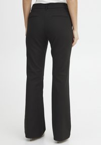 Pantaloni neri a campana realizzati in tessuto liscio, con vita aderente, due tasche posteriori e una finitura pulita senza hardware visibile.