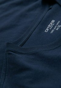 T-shirt in cotone blu navy con collo rotondo, texture morbida e etichetta con la scritta "100% cotone puro".