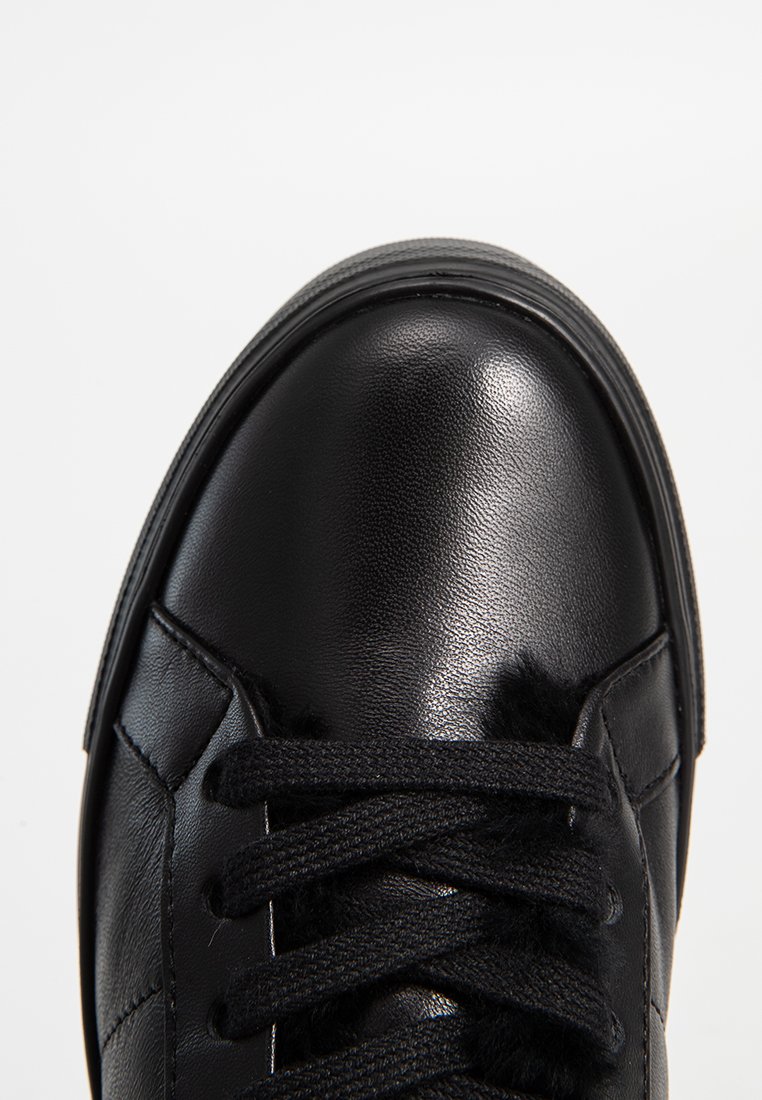 Czarne skórzane trampki z gładkim wykończeniem, okrągłym noskiem i teksturowanymi akcentami. Sznurówki sięgają na wierzch, a buty mają gumową podeszwę.