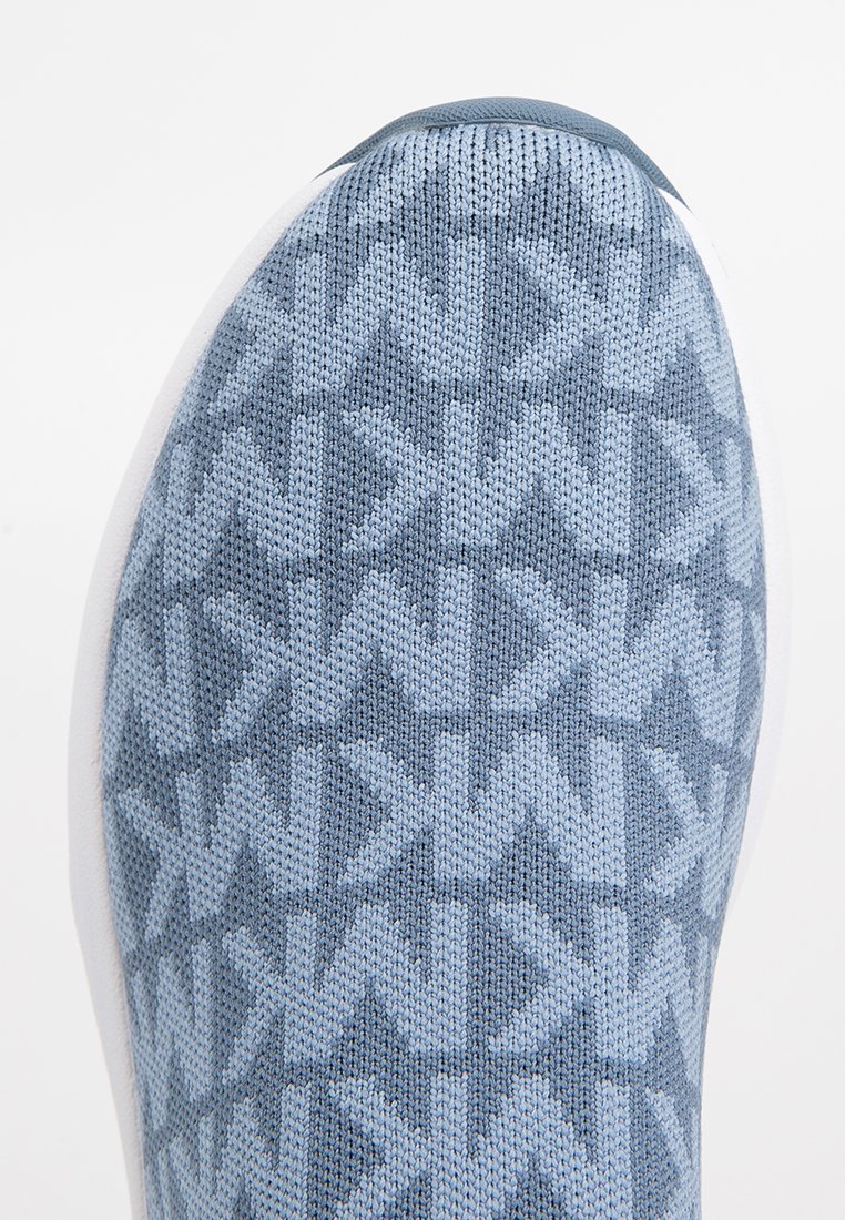 Chaussure de sport en tricot bleu avec un motif texturé en flèches, semelle en caoutchouc blanc et silhouette épurée.