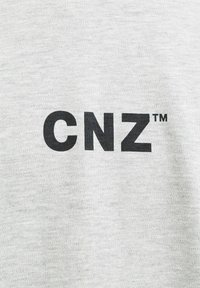 Grå bomuldsstof med et fremtrædende sort "CNZ™" logo. Teksturen er glat med et ribbet mønster.