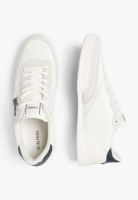 Adidași albi din suede și piele. Prezintă o talpă texturată, vârful perforat, accente gri și un tab de călcâi negru.