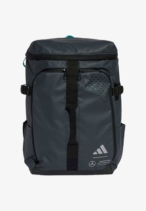Sac à dos gris foncé avec une fermeture éclair supérieure, des bretelles réglables, des poches avant, des détails perforés et les logos de Mercedes et Adidas.