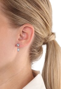 Ohrringe aus Sterlingsilber mit runder Oberseite und einem tropfenförmigen Anhänger, der klare Edelsteine, ein schlankes Design und eine polierte Oberfläche aufweist.