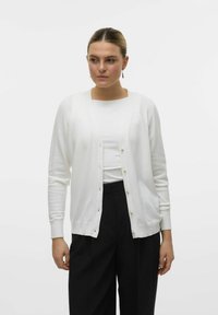 Cardigan bianco realizzato in un tessuto morbido, con scollatura a V, maniche lunghe e dettagli in bottoni dorati lungo la parte anteriore. Tessuto liscio.