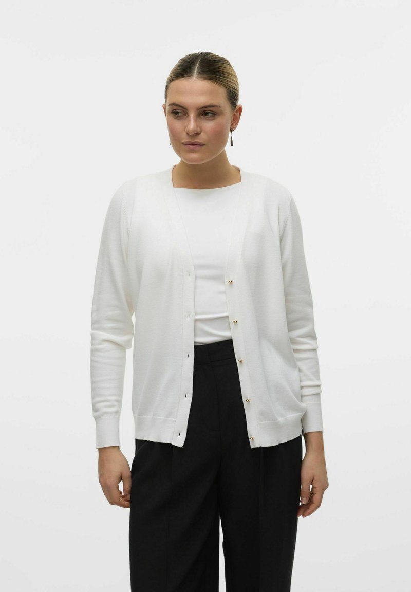 Cardigan bianco realizzato in un tessuto morbido, con scollatura a V, maniche lunghe e dettagli in bottoni dorati lungo la parte anteriore. Tessuto liscio.