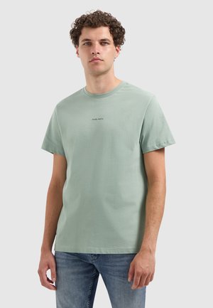 Mintgroene katoenen t-shirt met een ronde hals en korte mouwen, voorzien van eenvoudige zwarte tekst "PURE PATH" op de borst.