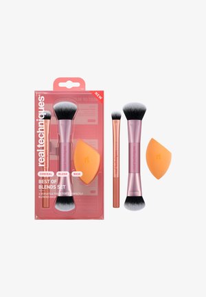 Drei Make-up-Pinsel mit pinkfarbenen Griffen und ein oranger Make-up-Schwamm mit Verpackung, auf der "Real Techniques Best of Blends Set" für Concealer, Rouge und Grundierung steht.