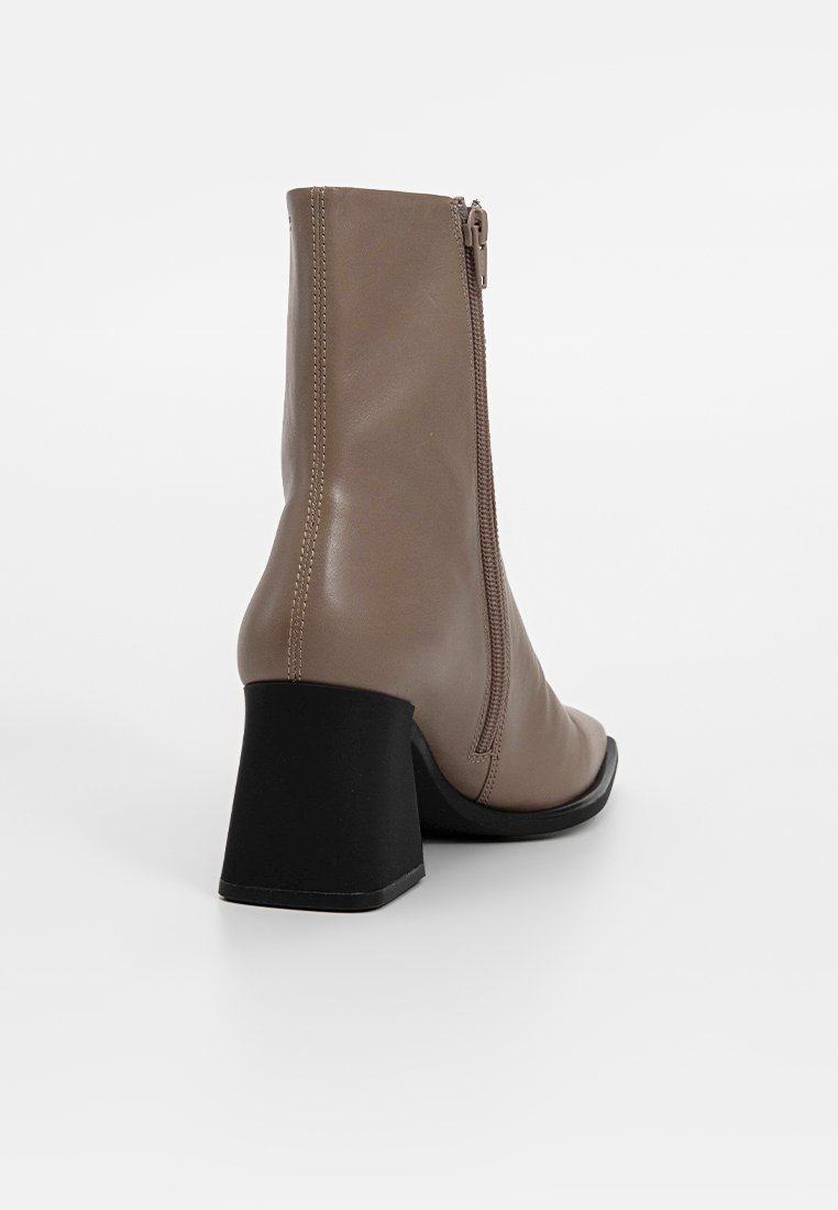 Bruine leren enkellaars met een blokhak, voorzien van een zijrits en een gladde textuur. De zool is zwart met een afgeronde punt.