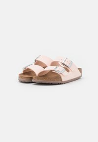 Sandali rosa chiaro con due cinturini regolabili, fibbie argentate e una soletta in sughero. La suola è marrone con una superficie testurizzata. Vestibilità regolabile.