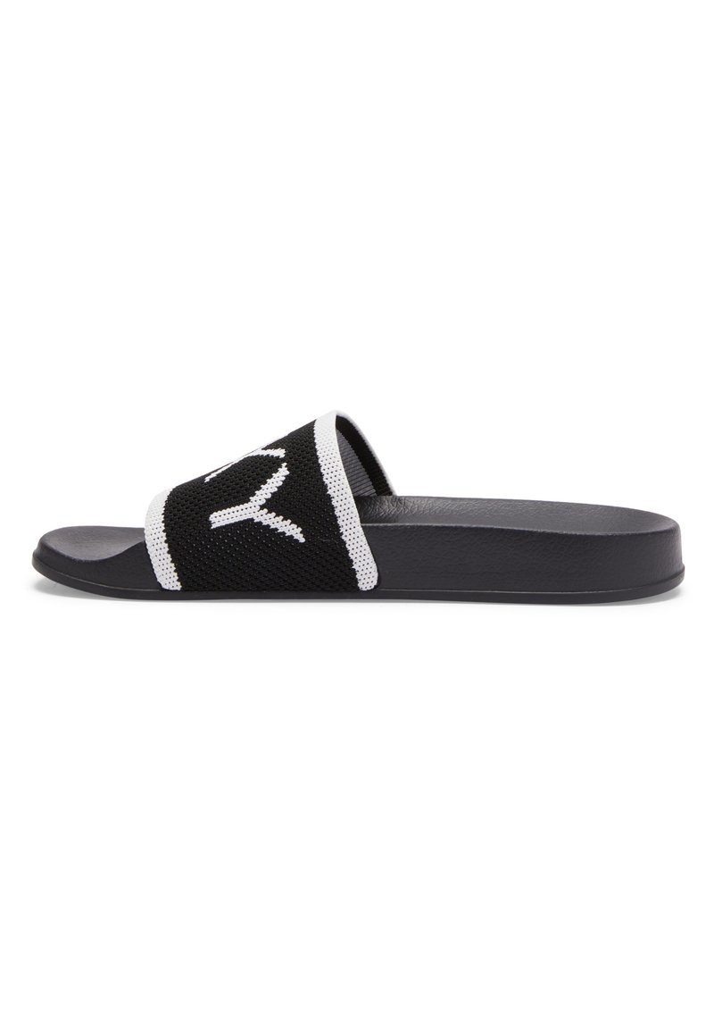 Sandal nera a slip con un morbido superiore in rete che presenta un design bianco. Suola piatta con finitura opaca, dalle linee eleganti e contrasti tattili.