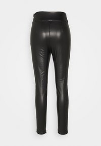 Leggings en faux cuir noir avec une coupe slim, une taille haute et des zips aux chevilles pour une longueur ajustable. Texture lisse avec une finition brillante.