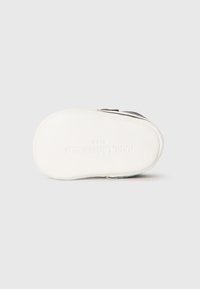 Białe półbuty dla dzieci z podeszwią w kolorze białym, na której wytłoczono napis "KARL LAGERFELD KIDS", widok od strony podeszwy.