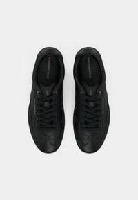 Μαύρα αθλητικά παπούτσια με λείο δερμάτινο επάνω μέρος, στρογγυλεμένο σχήμα, ραφές στο ίδιο χρώμα και επίπεδα κορδόνια· διαθέτουν ανάγλυφο λογότυπο στην εσωτερική σόλα.