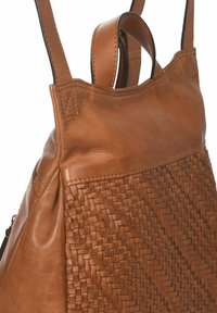 Mochila de cuero marrón con textura trenzada en el lateral, acabado suave en la parte superior y asas de transporte dobles.