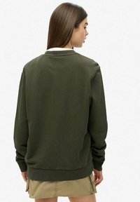 Sudadera de algodón verde oliva con un corte relajado, puños y dobladillo de canalé. Textura suave; presenta un diseño minimalista sin logotipos visibles.