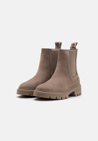 Bottines en suède marron avec des panneaux élastiques sur les côtés, semelle en caoutchouc plate et languette à l'arrière ; logo embossé sur le talon.