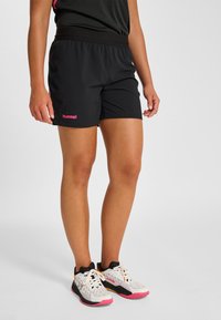 Svarta sportshorts med elastisk midja och en rosa logotyp på vänster sida. Kombineras med lätta, mönstrade sneakers med rosa detaljer.