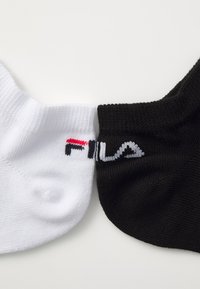 Dva páry ponožiek do členkov: jedny biele a jedny čierne, každé s logom "FILA" v kontrastných farbách. Textília vyzerá štruktúrovaná.