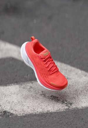 Sapatilha atlética neon laranja com parte superior em rede, entressola branca e detalhes em preto. Apresenta um bico arredondado e uma aba no calcanhar.