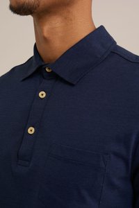 Námořnická modrá polo košile se strukturovaným límcem, třemi zlatými knoflíky a malou kapsičkou na prsou. Tkanina má hladkou texturu.