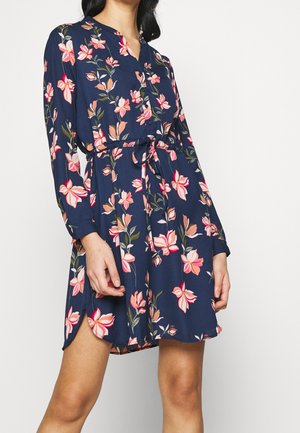 Abito floreale in navy con stampe di fiori rosa e pesca, chiusura a bottoni, maniche lunghe e vita regolabile con lacci. Tessuto morbido e leggero.