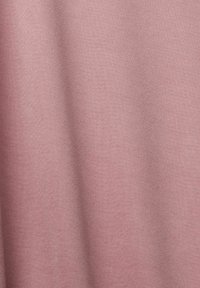Tissu rose poudré doux avec une texture à tissage fin et de plis subtils créant des ombres et des reflets délicats.