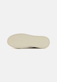 Semelle de sneaker en caoutchouc beige, à design plat. Surface texturée avec une prise en main à motif pour l'adhérence. Bords arrondis, sans logos ni embellissements.