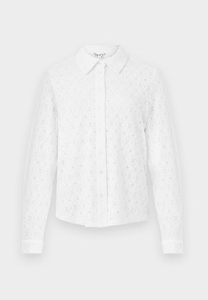 Chemise blanche à boutons, en dentelle texturée, avec col, manches longues et patte de boutonnage à l'avant. Motif floral sur l'ensemble.