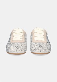 Zapatillas con un upper texturizado en plata cubierto de pequeños strass, detalles en crema y cordones planos; suela de goma visible en la parte inferior.