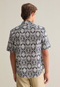 Korte mouw shirt met een zwart-wit bloemenpatroon, gemaakt van lichte stof met een klassieke kraag en een gebogen zoom.