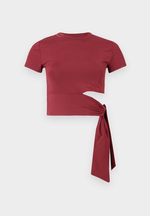 Camiseta ajustada de manga corta en rojo intenso, con un detalle recortado y un lazo en el lateral para un diseño único. Tejido suave.