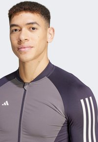 Athletic long-sleeve shirt in gray and dark navy, featuring a zip front, round collar, and three white stripes on the shoulder.