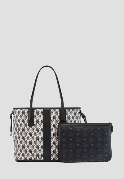 Designer-Tasche mit geometrischem Muster und schwarzen Lederakzenten, kombiniert mit einem kleineren schwarzen Beutel mit einem subtilen Logo-Muster.