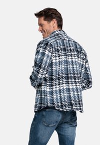 Geruite blouse in blauwtinten en wit, met een losse pasvorm, lange mouwen en een knoopsluiting. Kenmerkend ruitpatroon.