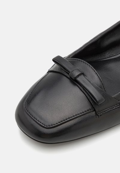 Schwarze Lederflats mit quadratischer Zehenform, die an der Vorderseite eine Schleifenakzentuierung und eine dezente Textur aufweisen. Das Innere ist glatt und ohne sichtbare Nähte.
