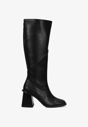 Botte noire en cuir montant jusqu'au genou avec un bout carré et un talon chunky, présentant un élément de design diagonal le long de la tige pour un détail supplémentaire.
