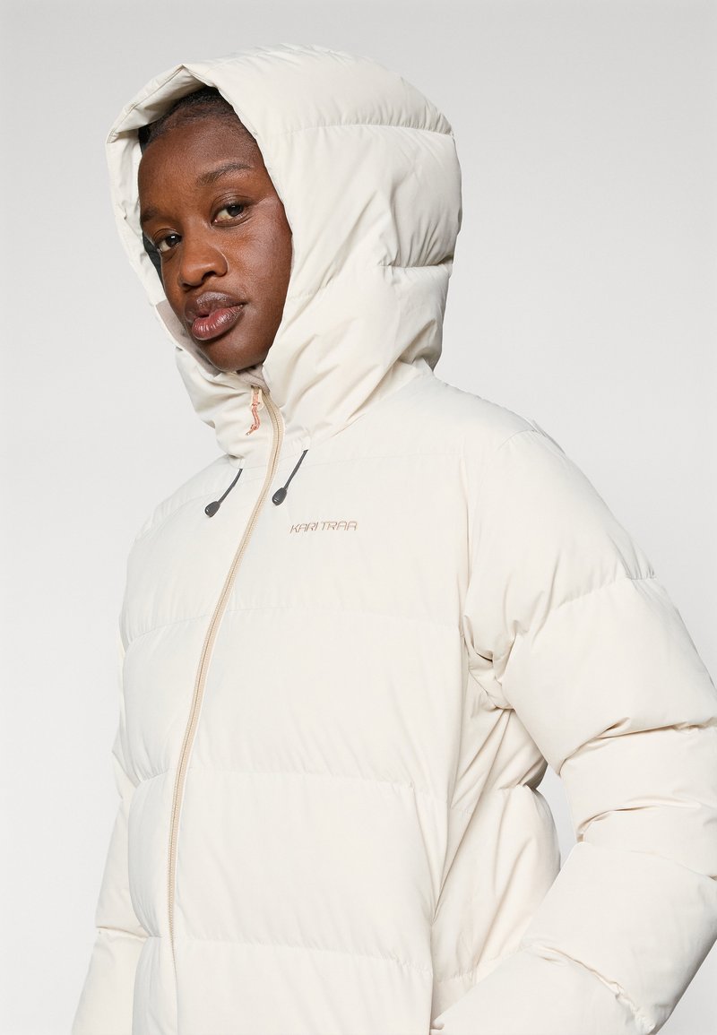 Kurtka puchowa w jasnym beżu z kapturem, z pikowanym wzorem, z zamkiem z przodu oraz sznurkami w kapturze do regulacji dopasowania.