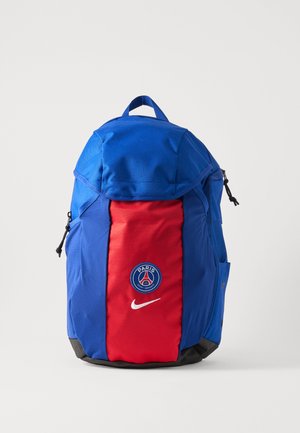 Rucsac albastru și roșu cu logo-ul Paris Saint-Germain și simbolul alb Nike în față, în picioare pe un fundal alb.