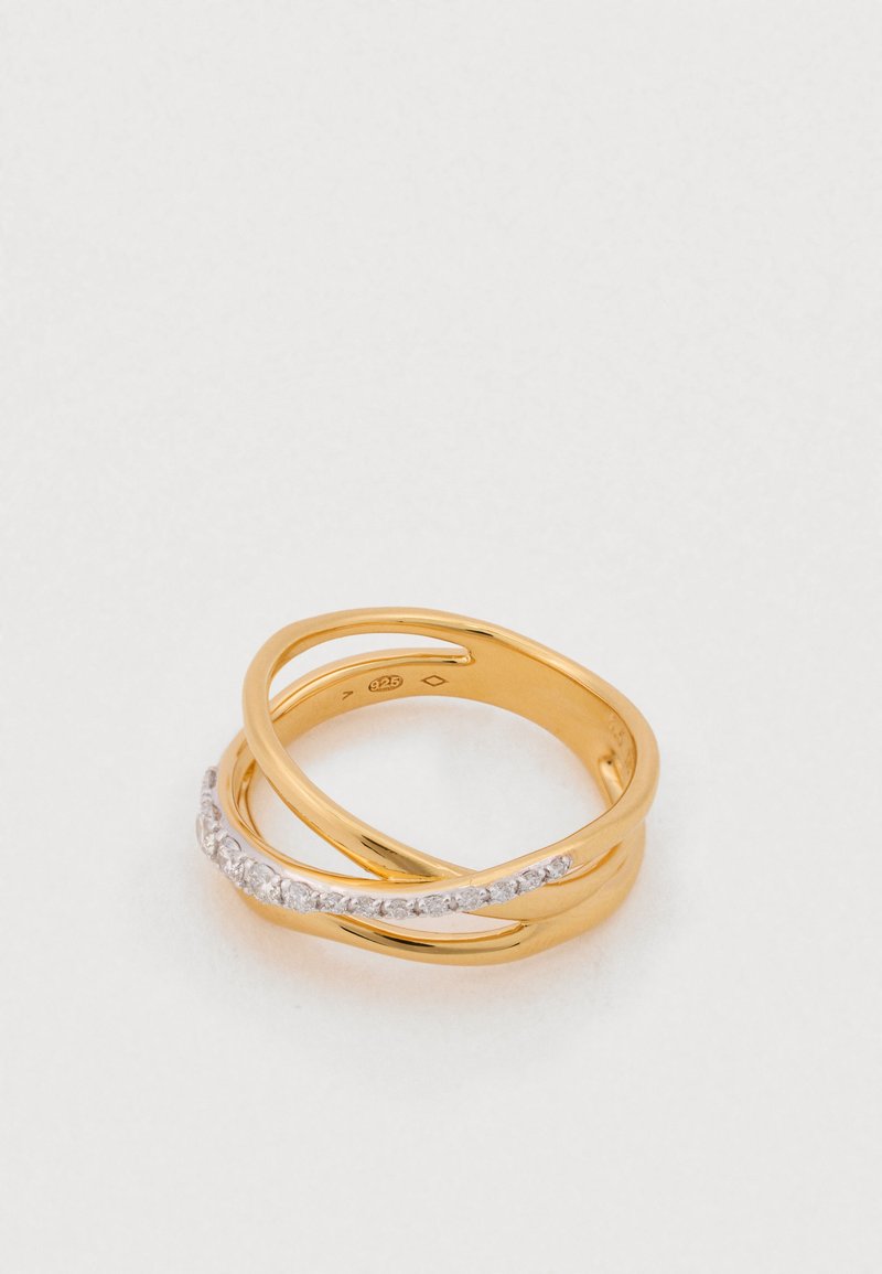 Auksinės spalvos žiedas, sudarytas iš dviejų susipynusių juostelių: viena lygi ir poliruota, kita puošni su eilute skaidrių, blizgančių brangakmenių.