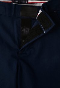 Mörkblå shorts med ett kardborreband i midjan och ett randigt innerfoder, som visar en mjuk yta och skräddarsydd design.