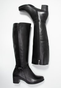 Botas altas de cuero negro hasta la rodilla con tacón cuadrado, que cuentan con una cremallera lateral, una correa decorativa con acentos y una textura suave y brillante.