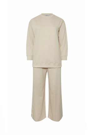 Sweatshirt en coton beige avec des manches longues et un col rond, associé à un pantalon large, tous deux présentant une finition douce et texturée.