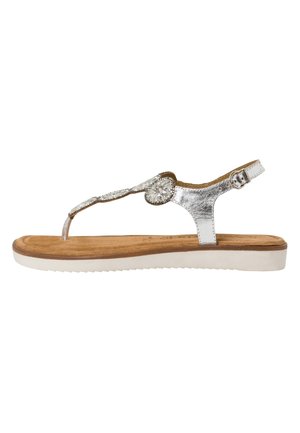 Silver metallic thong sandal with a circular embellishment, cushioned tan footbed, and a white rubber sole. Adjustable ankle strap included.