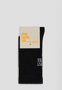 Schwarze gerippte Socken mit einem umgeschlagenen Bündchen, das orangefarbene und weiße Schriftzüge auf der Oberfläche zeigt. Kommt mit einem beigen Etikett, das den Markennamen zeigt.
