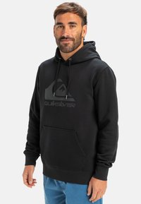 Fekete kapucnis felső, puha anyagból, kenguru zsebbel és egy nagy szürke Quiksilver logóval. Állítható, zsinórral ellátott kapucnival rendelkezik.