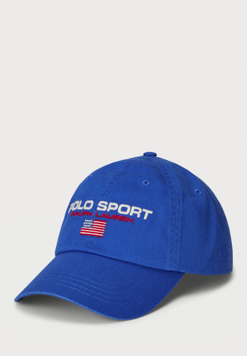 Gorra de béisbol azul hecha de algodón. Presenta el texto bordado "POLO SPORT" y "RALPH LAUREN", junto con una pequeña bandera estadounidense.