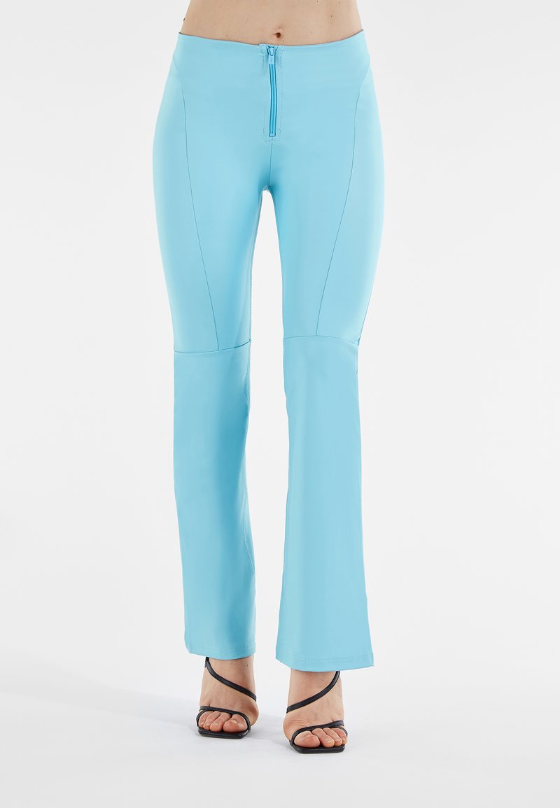 Pantaloni flared blu chiaro con zip frontale e dettagli cucitura. Realizzati in tessuto morbido ed elastico, progettati per il comfort e la mobilità.