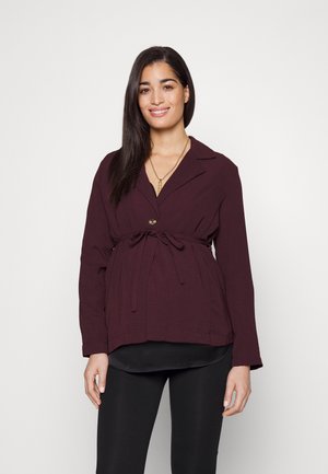 Μαρούλι μπλούζα με γιακά, μακριά μανίκια και ζώνη που δένει στη μέση. Διαθέτει κλείσιμο με έναν μόνο κουμπί και υφή υφάσματος.